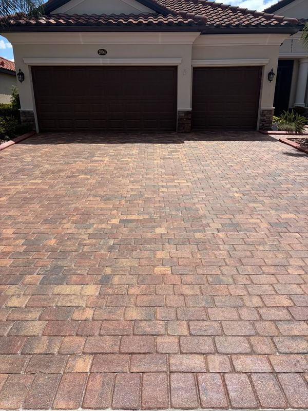 Wide brick paver driveway in front of a three car garage