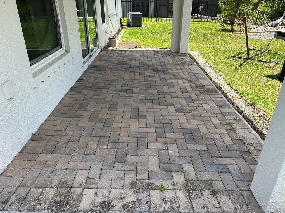 The same lanai pavers before cleaning, grey with algae staining and weeds